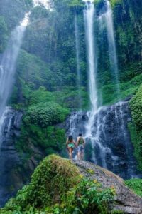 couple holding hands and admiring Sekumpul waterfall in Bali, Indonesia