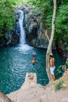 Local Balinese guide jumping onto Kroya waterfall Bali, Indonesia