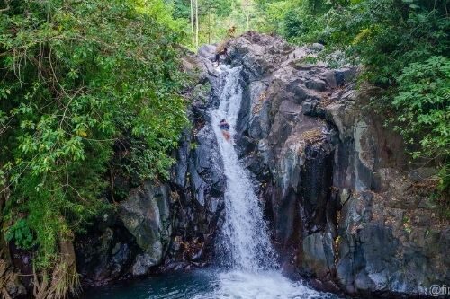 Woman sliding down onto Kroya Waterfall Bali, Indonesia