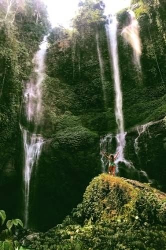 island girl, standing on a boulder in front of Sekumpul waterfall, bali, indonesia