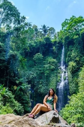 smiling woman, sitting on a boulder, sekumpul waterfall, bali indonesia